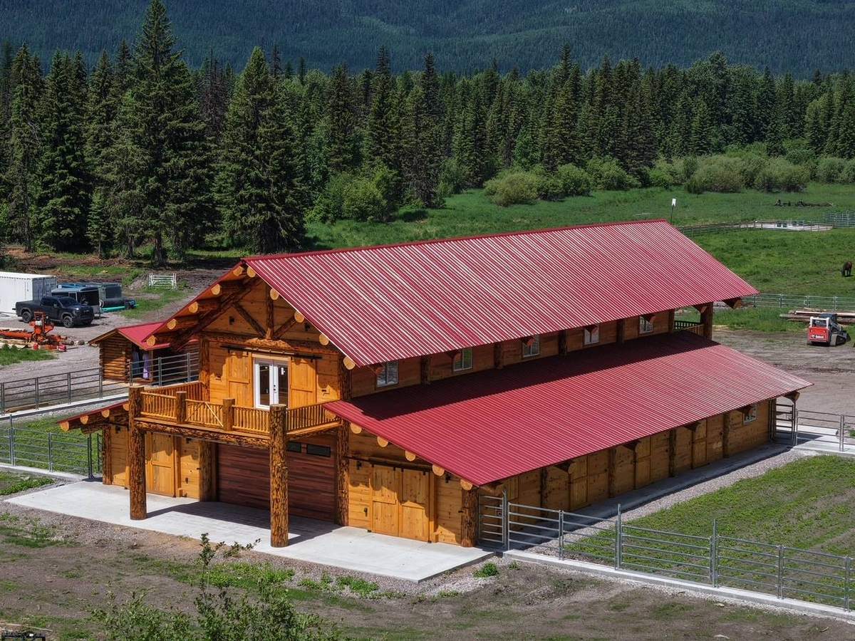 Finished log barn with red metal roof from the air