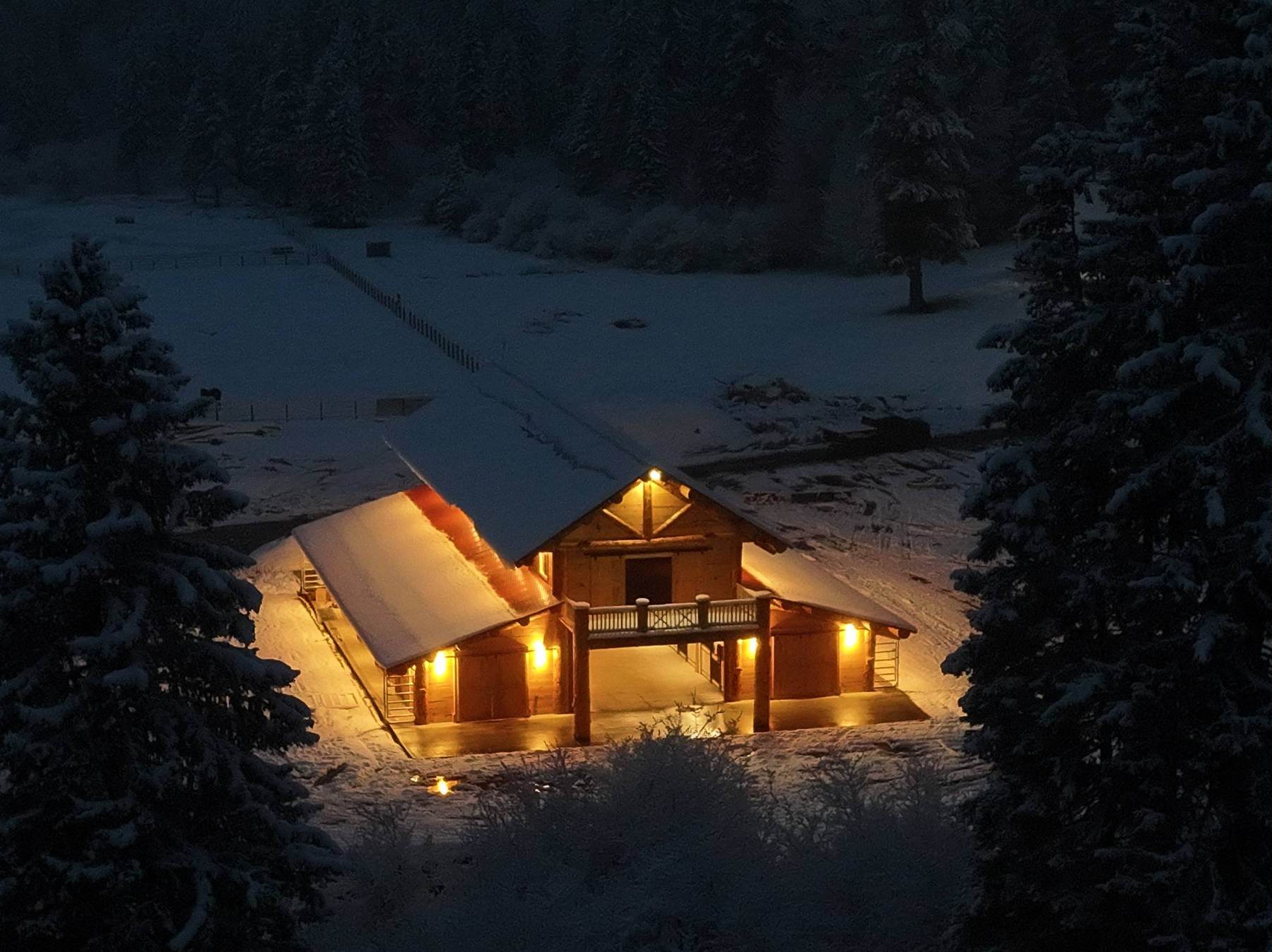 The barn at dusk from the air, lights on, snow on the ground