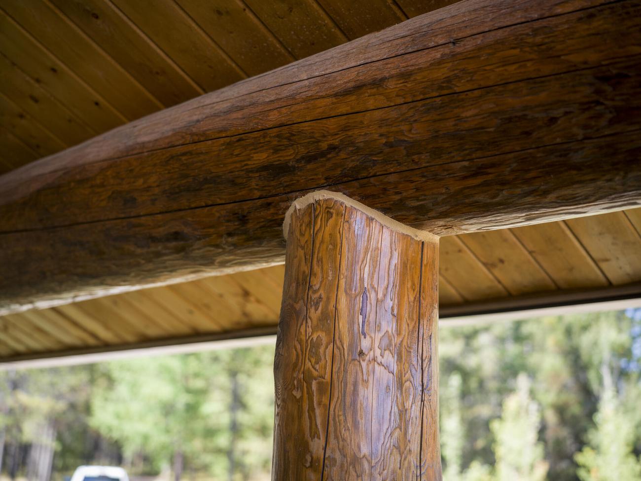 Log post meeting a squared beam beneath a porch roof