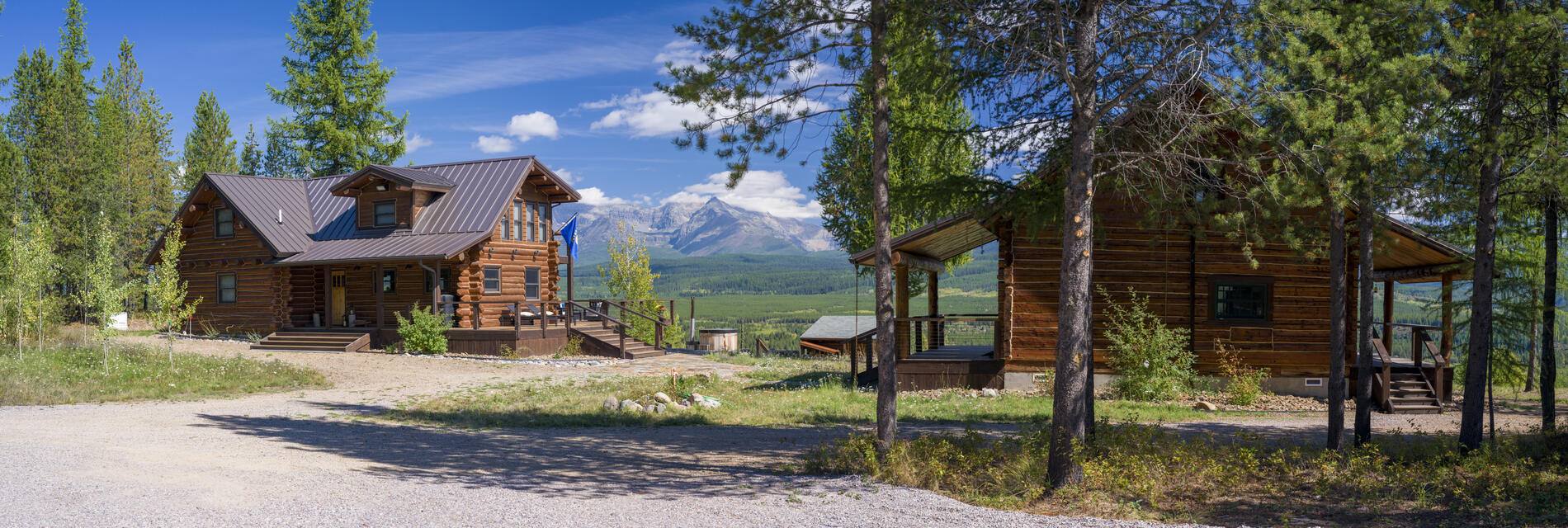 Two log cabins on a bench above the North Fork valley with mountains behind